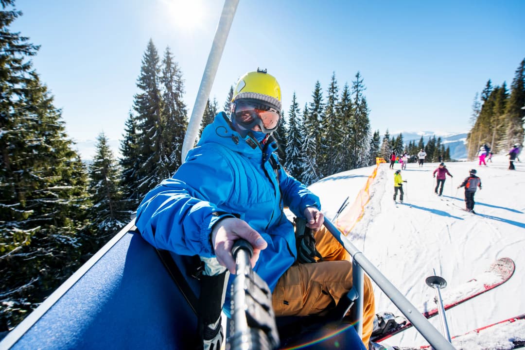 male skier using selfie stick taking photos